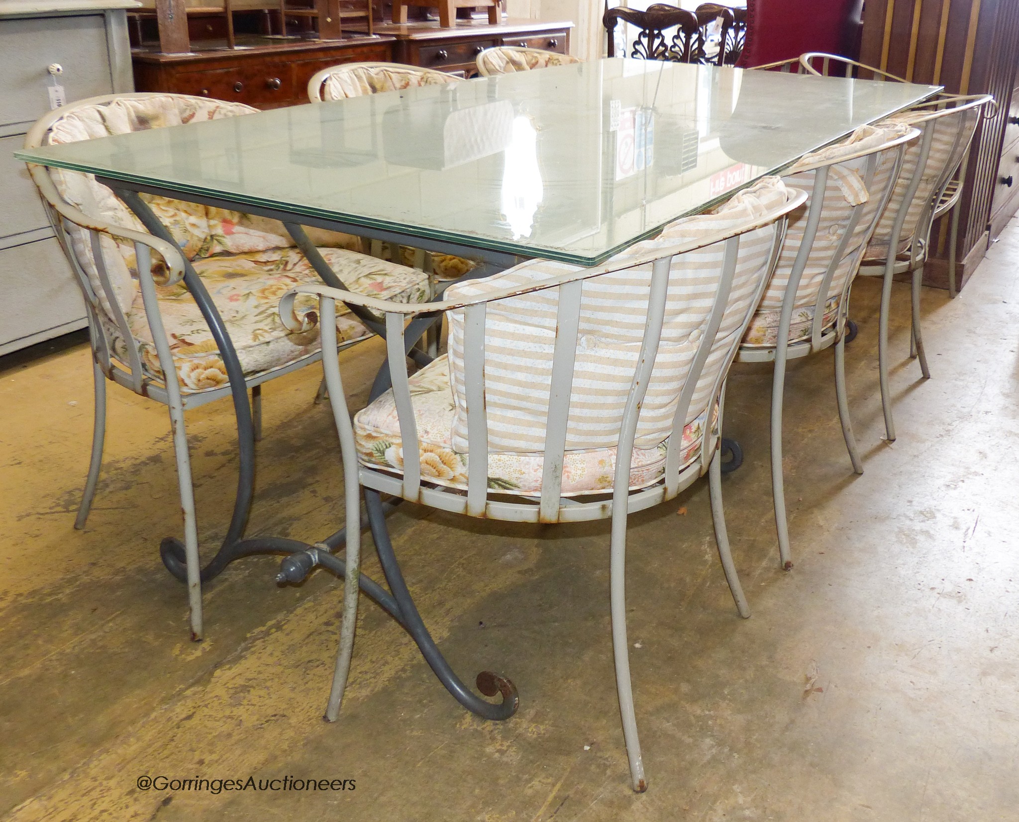 A rectangular glass topped wrought iron garden table and eight chairs. Table, 200x100x75cm.